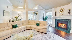 A spacious living room with a large beige sectional sofa, a glass coffee table, and a fireplace. - Walk to Lake! Rowlett Escape w/ Fire Pit & Views (Rowlett)