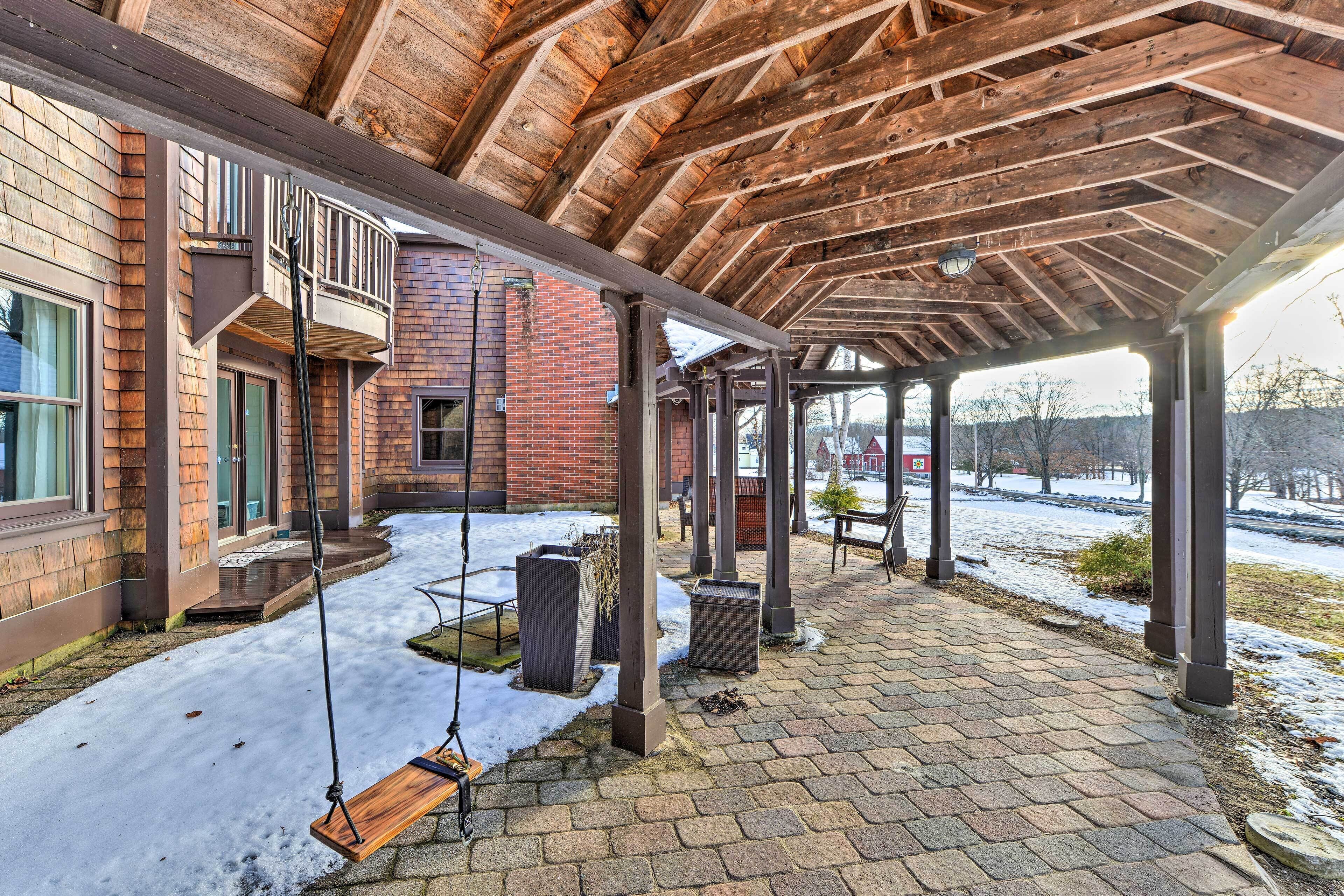 A covered outdoor area with a wooden ceiling, brick walls, and a swing.