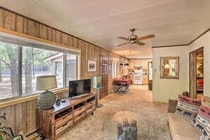 A spacious living room with a large TV, wooden entertainment unit, and a glass coffee table. - Show Low Cabin w/ Fire Pit: Near Hiking! (Show Low)