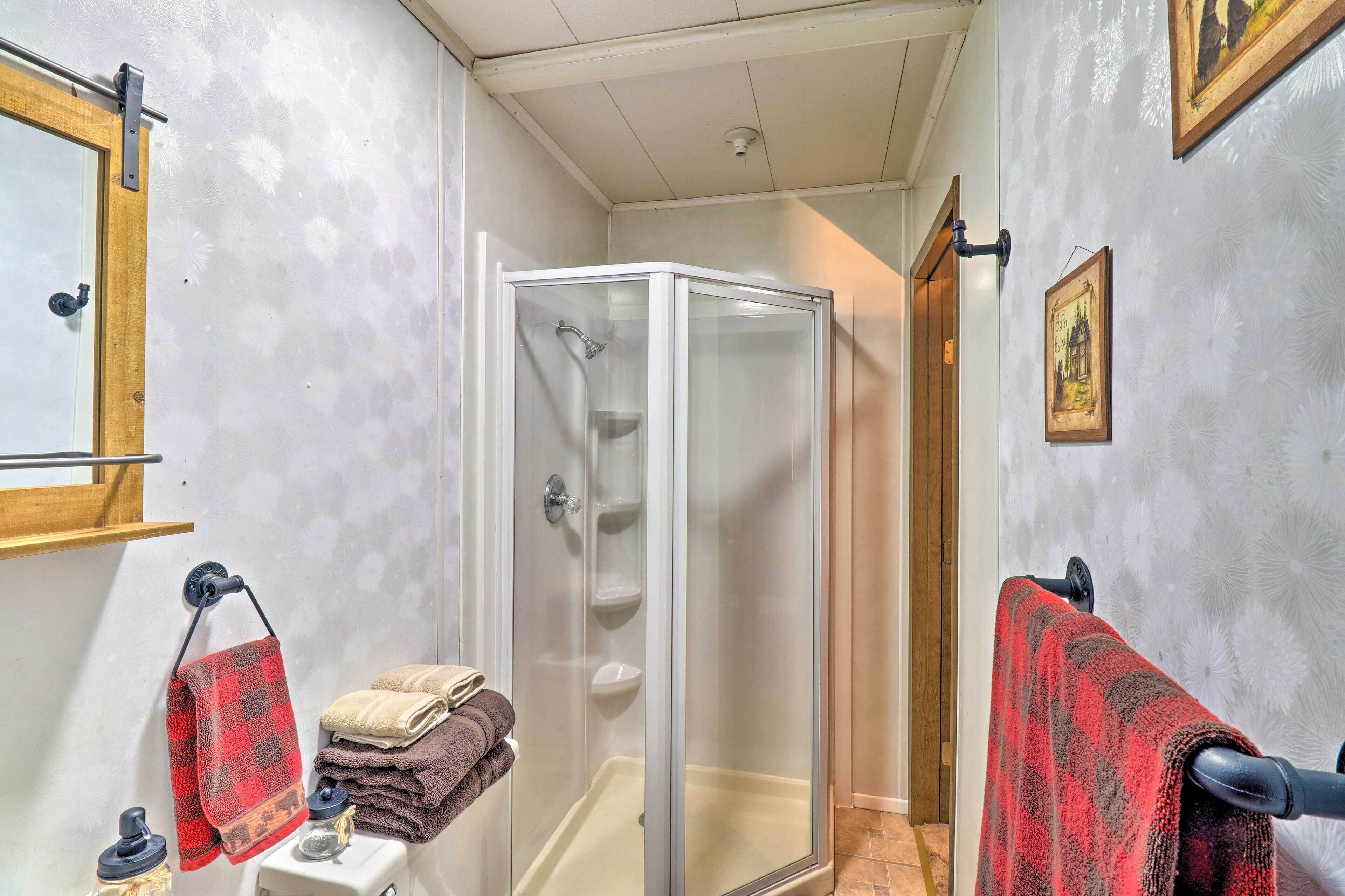 A bathroom with a glass shower enclosure, a sink with a towel rack, and a mirror.