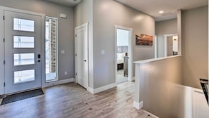A modern interior with a wooden floor, a staircase, and a door leading to another room. - Stunning Grand Junction Home Near Downtown! (Grand Junction)