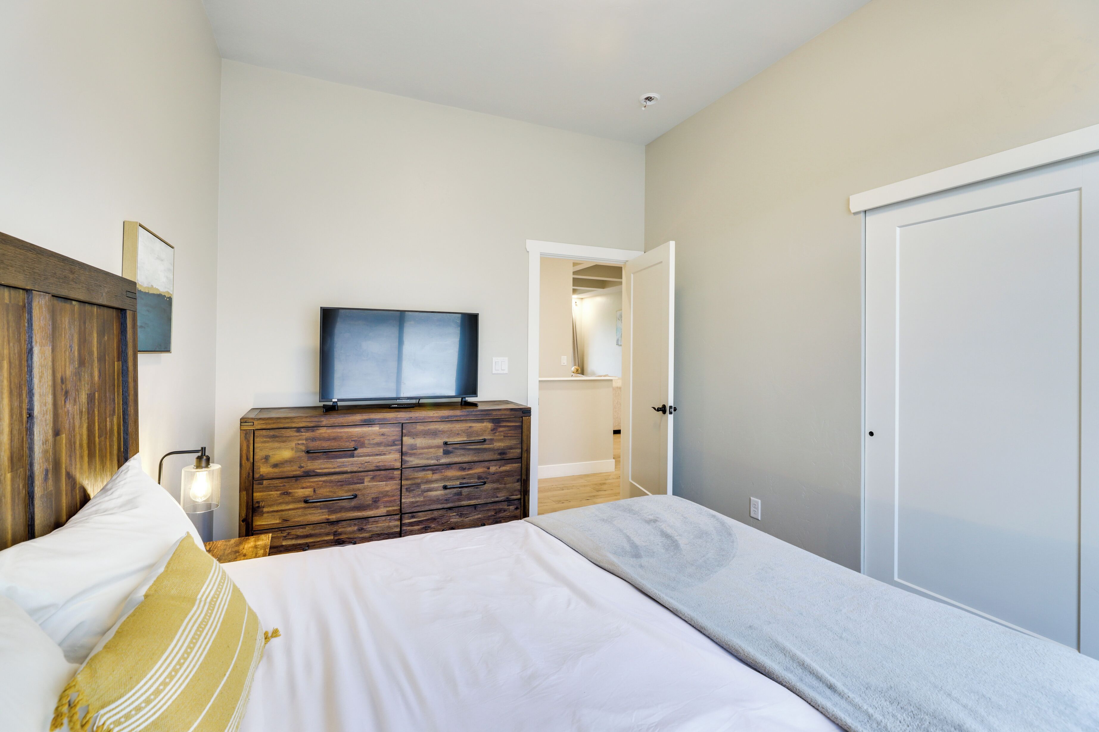 A bedroom with a bed, wooden dresser, and a television on top.