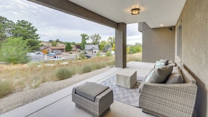 An outdoor patio with wicker furniture, a concrete floor, and a view of a residential area. - Stunning Grand Junction Home Near Downtown! (Grand Junction)