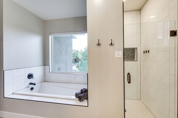 Un baño moderno con una bañera grande, zona de ducha y ventana que proporciona luz natural.