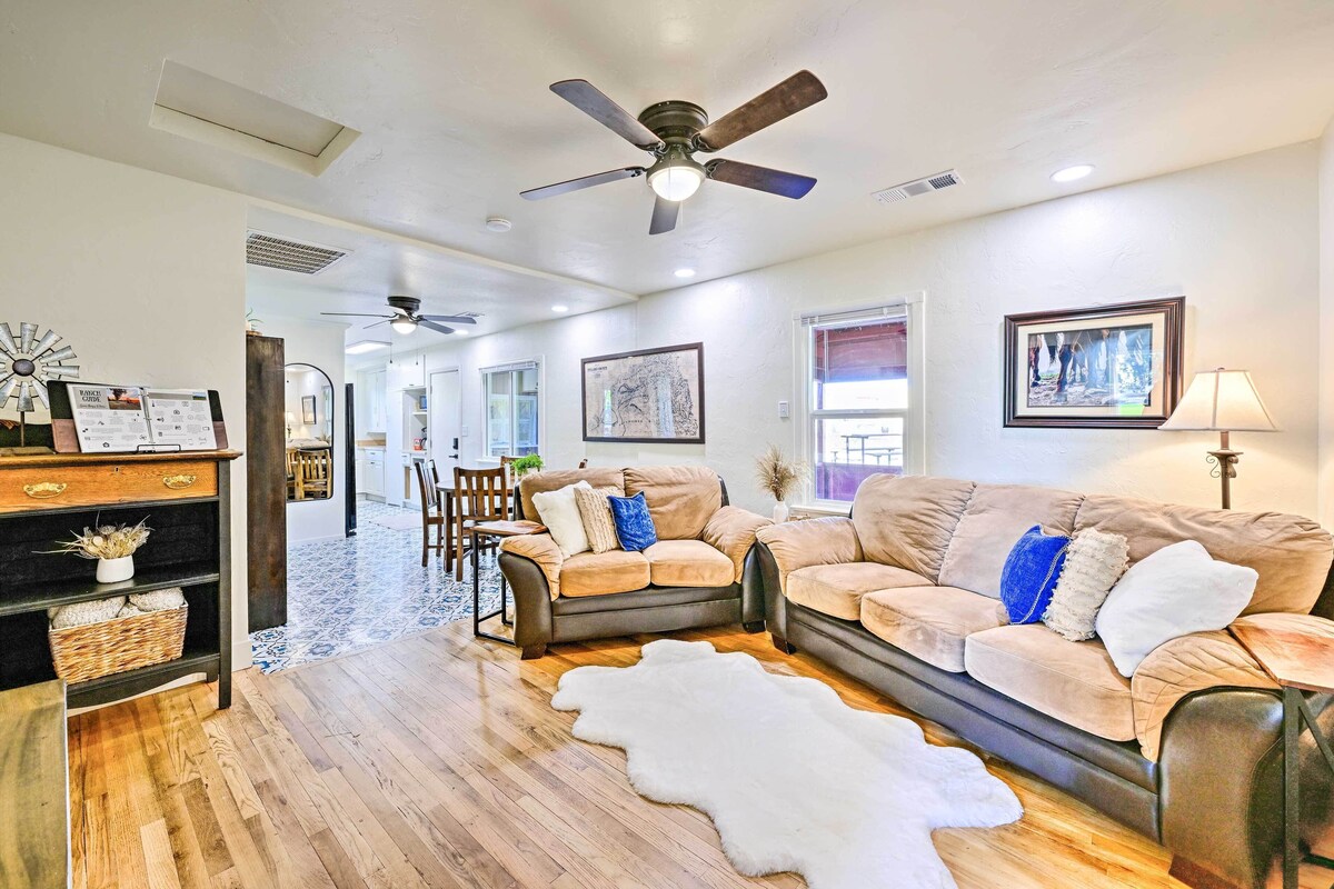 A spacious living room with a ceiling fan, a large window, and a wooden floor.
