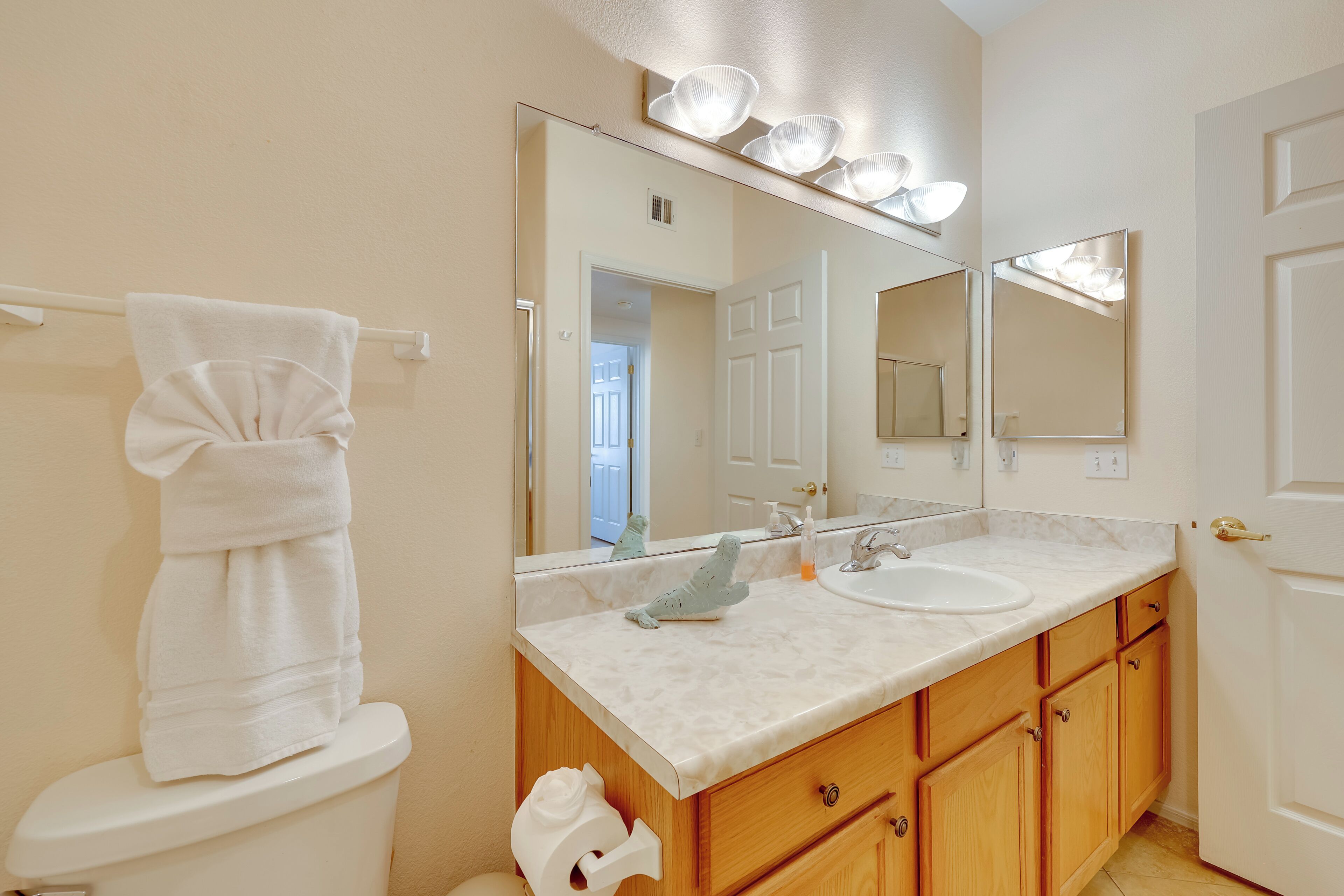 Une salle de bain équipée de toilettes, d’un lavabo, d’un miroir et de meubles en bois.