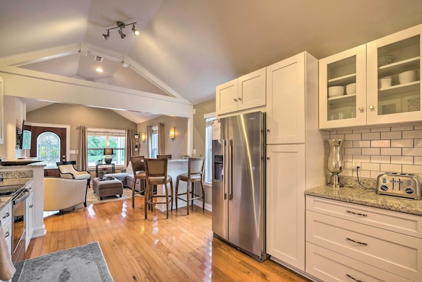 A kitchen with white cabinets, a stainless steel refrigerator, and a granite countertop.