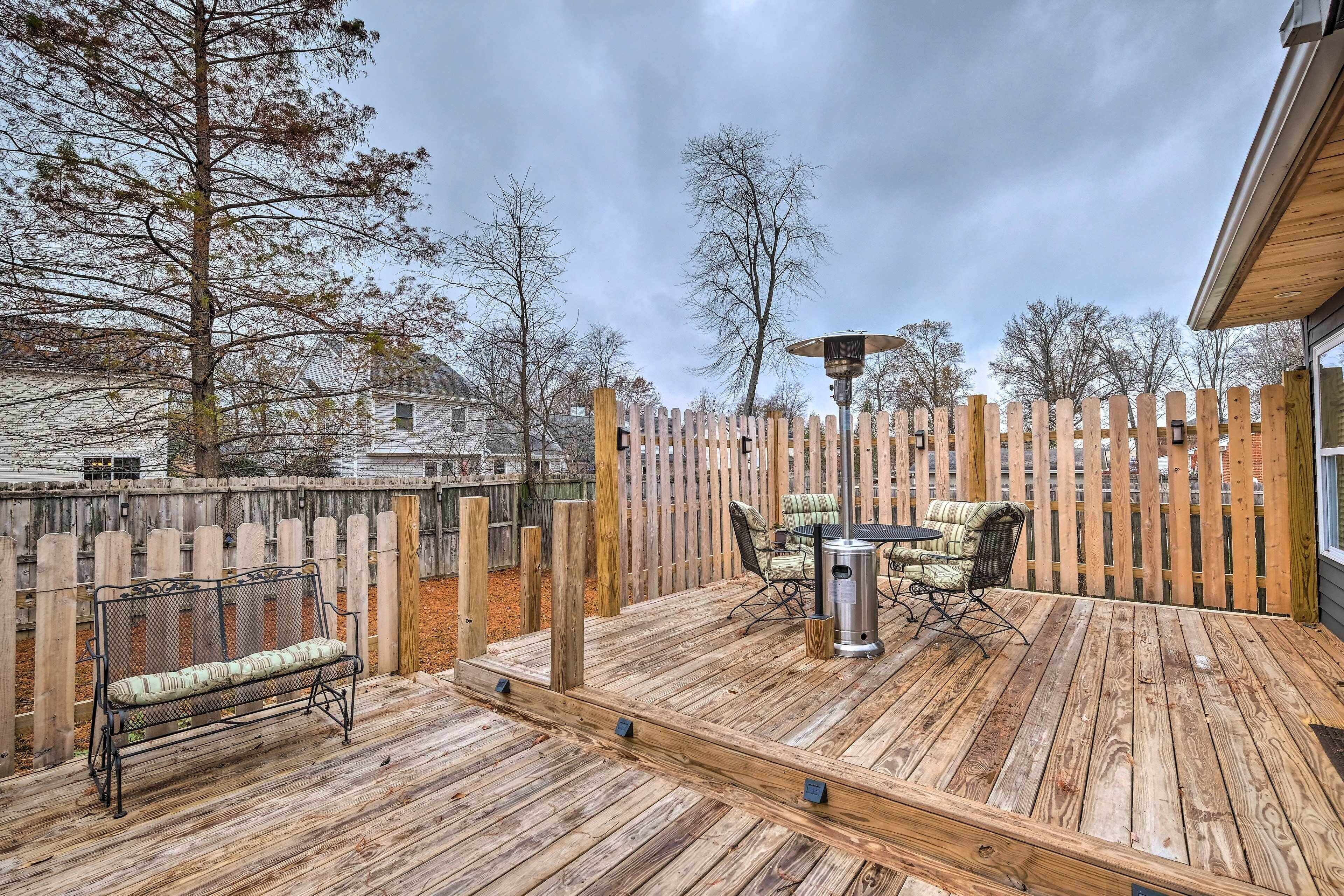 A wooden deck with a bench and a table with chairs, surrounded by a wooden fence.