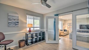 A modern living room with a ceiling fan, a sofa, a coffee table, and a sliding glass door leading to another room. - Near Golfing: Mesa Escape w/ Pool & Yard (Mesa)