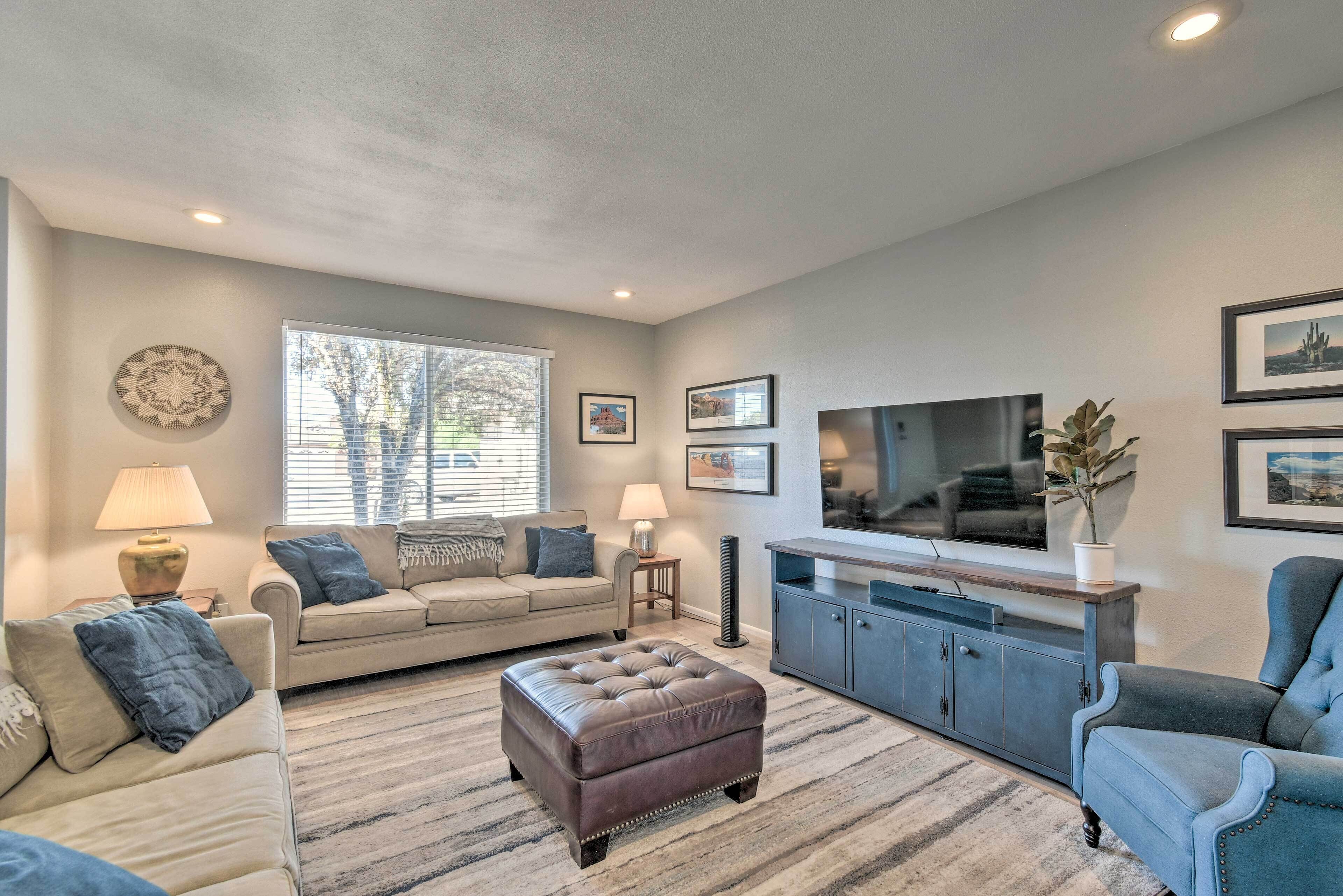 A living room with a sofa, ottoman, and armchair, a TV, and a cabinet.