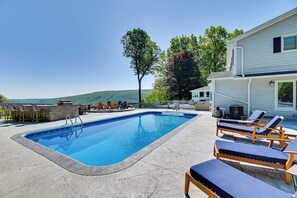 A swimming pool with lounge chairs, a barbecue area, and a view of the hills. - Finger Lakes Vacation Rental w/ Hot Tub & Pool (Naples)