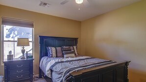Une chambre à coucher avec un lit, une table de chevet, une lampe et une fenêtre avec des stores.