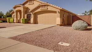 Une maison de plain-pied à la façade beige, avec un garage et une allée gravillonnée.