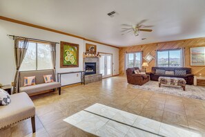 A spacious living room with a fireplace, sofas, and a view of the mountains. - Private Hot Tub & Epic Views in Superstition Mtns! (Apache Junction)