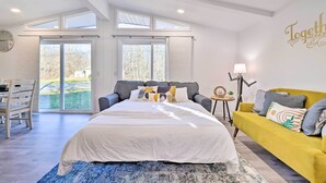 Un dormitorio con una cama grande, un sofá amarillo y vistas al exterior a través de amplios ventanales.