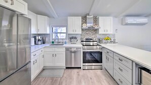 Una cocina moderna con armarios blancos, electrodomésticos de acero inoxidable y un salpicadero de azulejos.