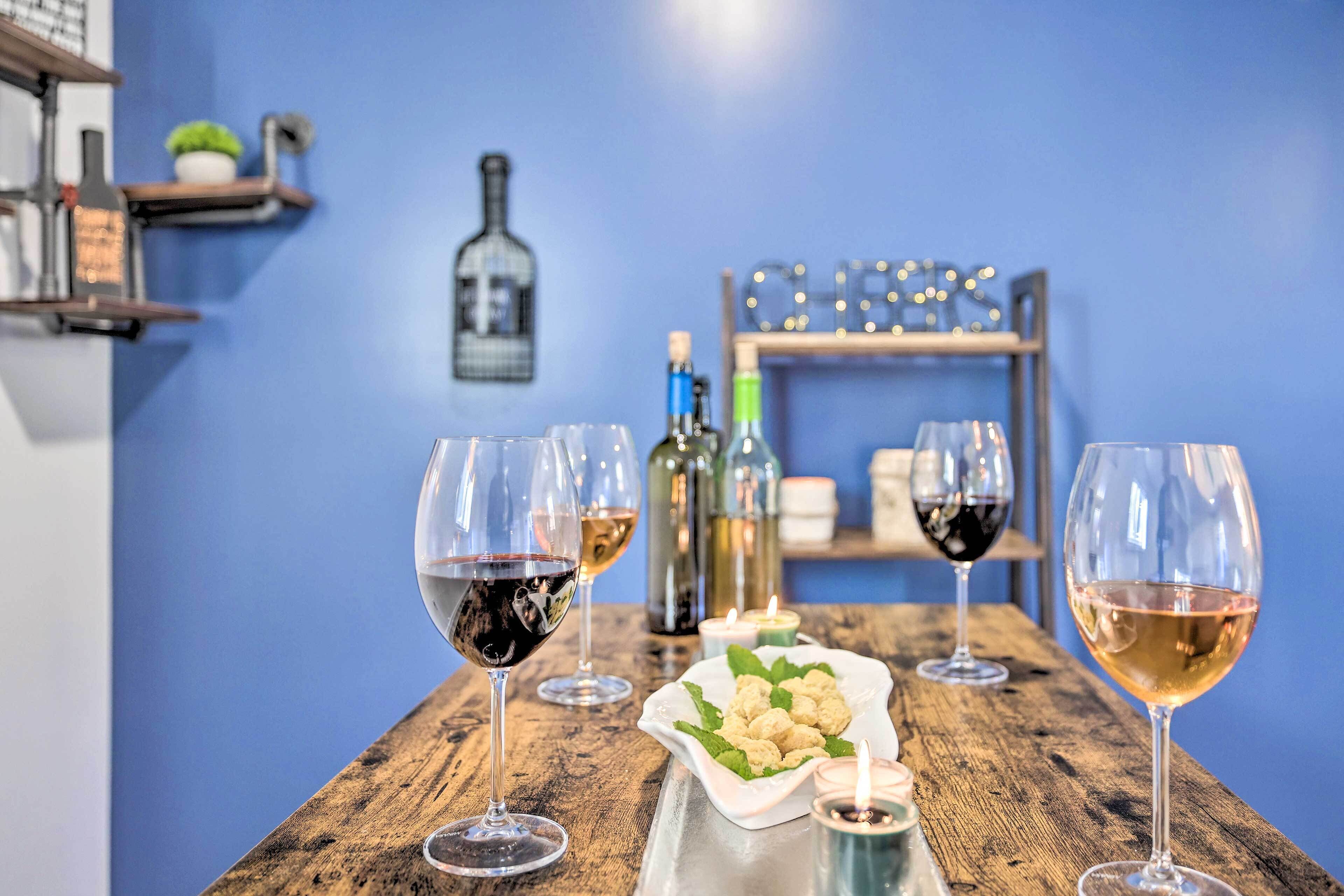 Un tavolo di legno con bicchieri e bottiglie di vino, un piatto di cibo e candele.
