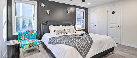 A bedroom with a large bed, a ceiling fan, and a window with a view of trees.
