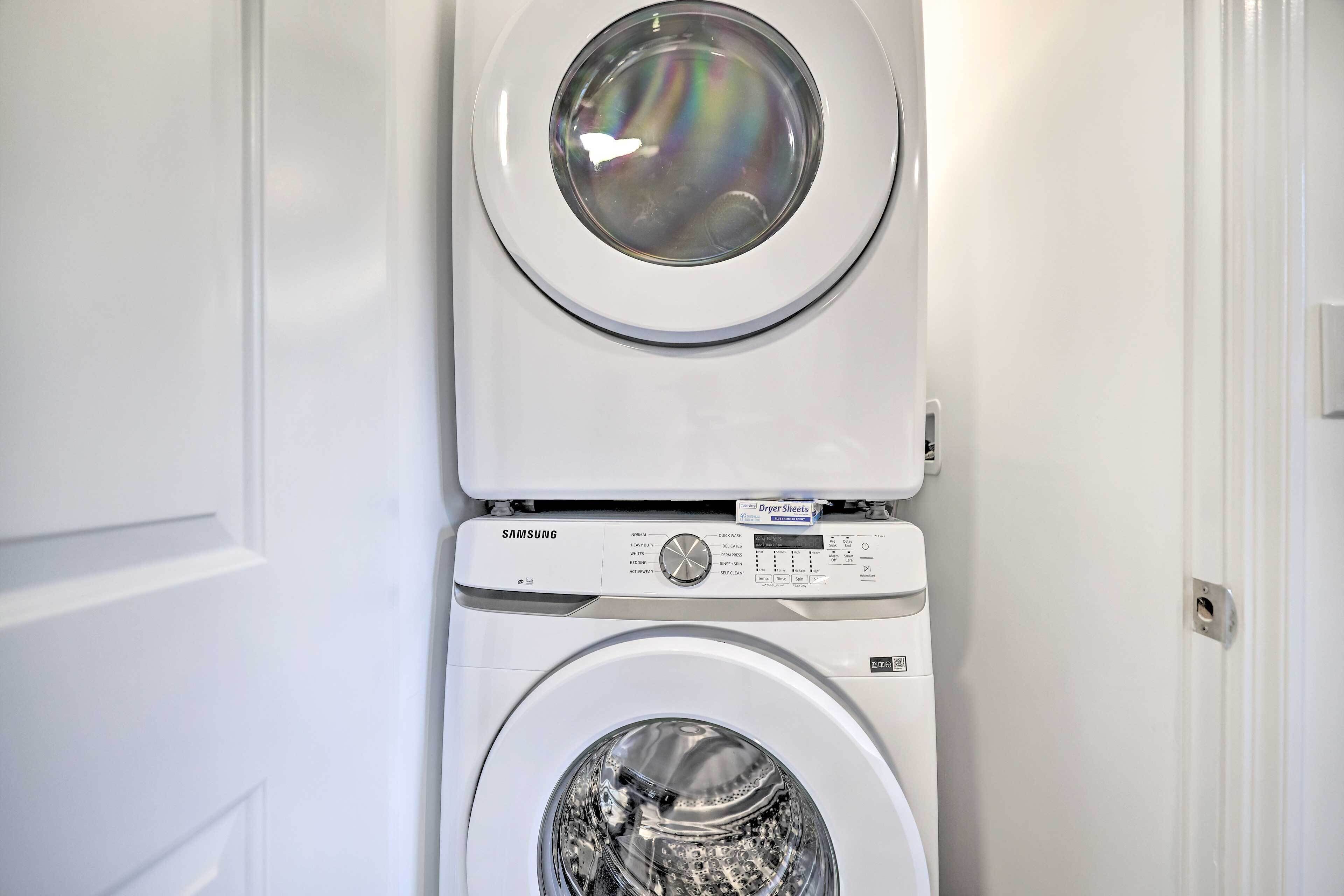 Una lavadora y secadora apiladas en una habitación con una puerta blanca.