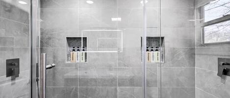 A modern shower with glass doors, a rain showerhead, and a built-in soap dispenser.