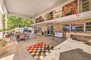 A spacious outdoor area with a checkered floor, tables, chairs, and a view of a restaurant in the background. - Rustic Dog-friendly Cabin w/ Deck & Fire Pit! (Murray)