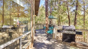 A deck with a grill, outdoor furniture, and a view of the surrounding forest. - Deck + Game Room: Lakeside 'blue Jay Chalet' Cabin (Lakeside)