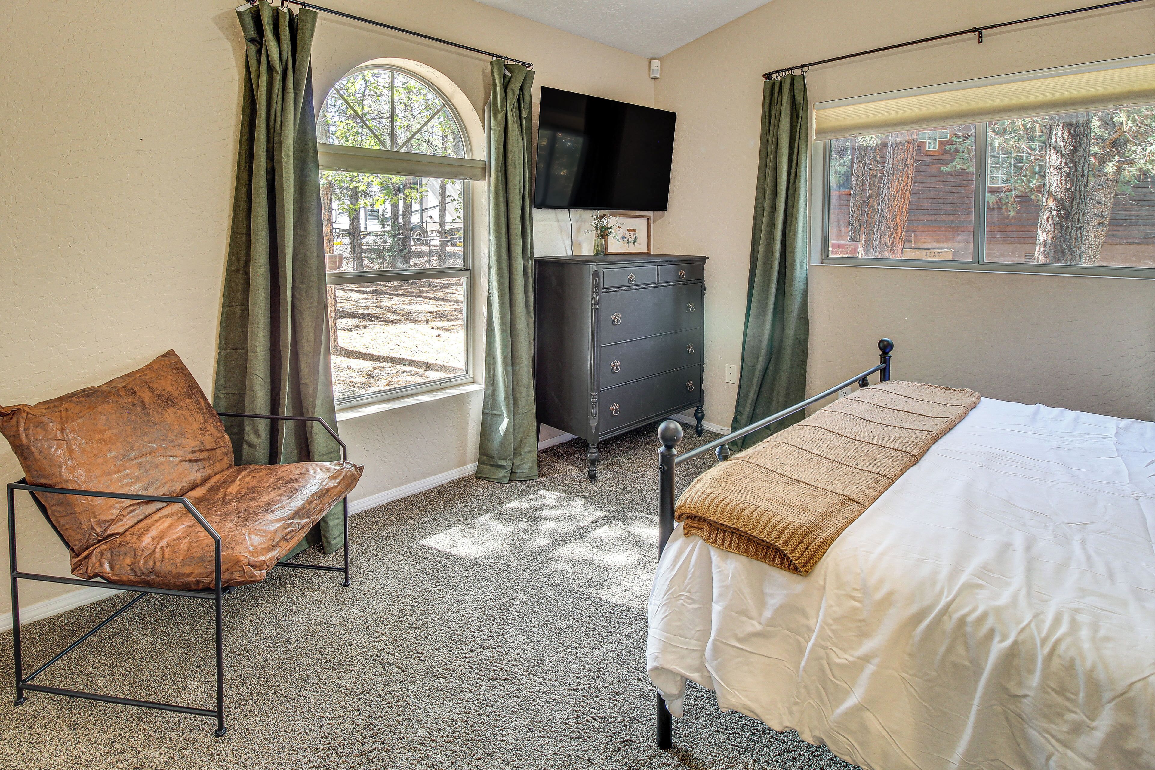 Ein Schlafzimmer mit einem Bett, einem Sessel, einem Schminktisch und einem Fernseher.