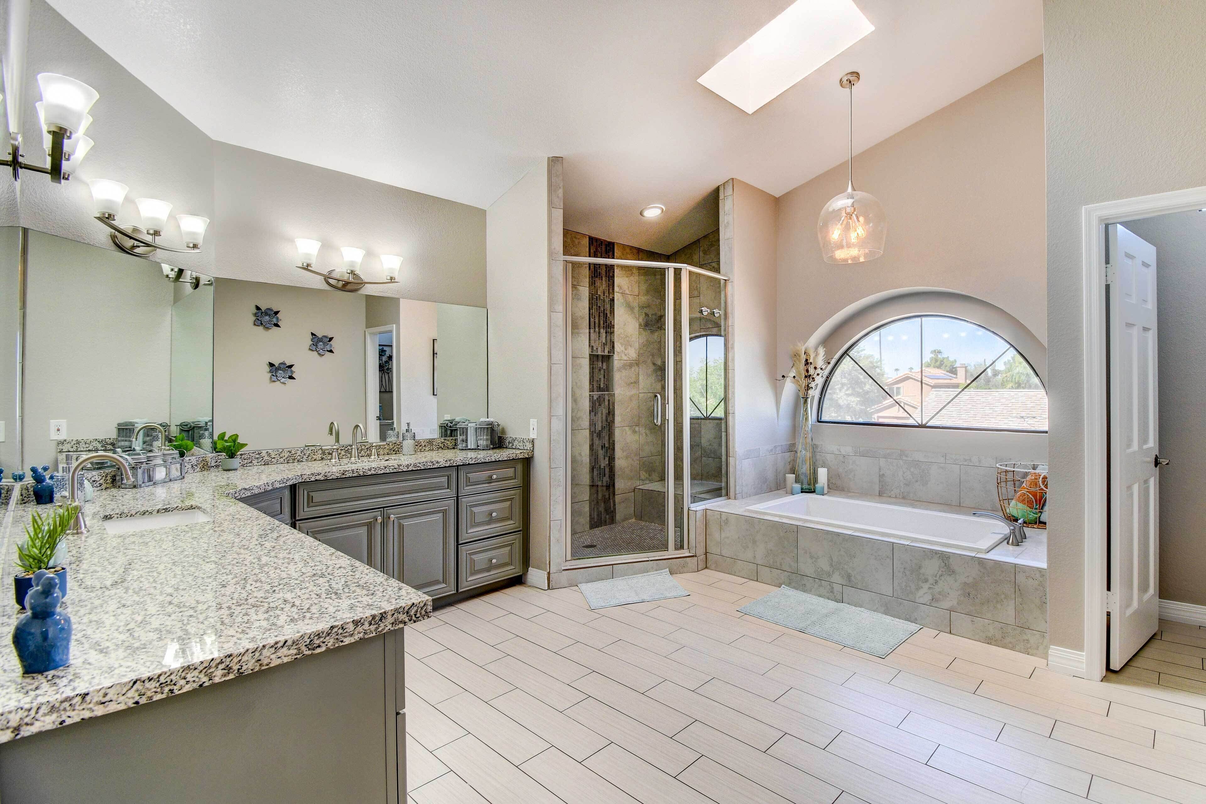 A modern bathroom with a large vanity, a walk-in shower, and a bathtub.