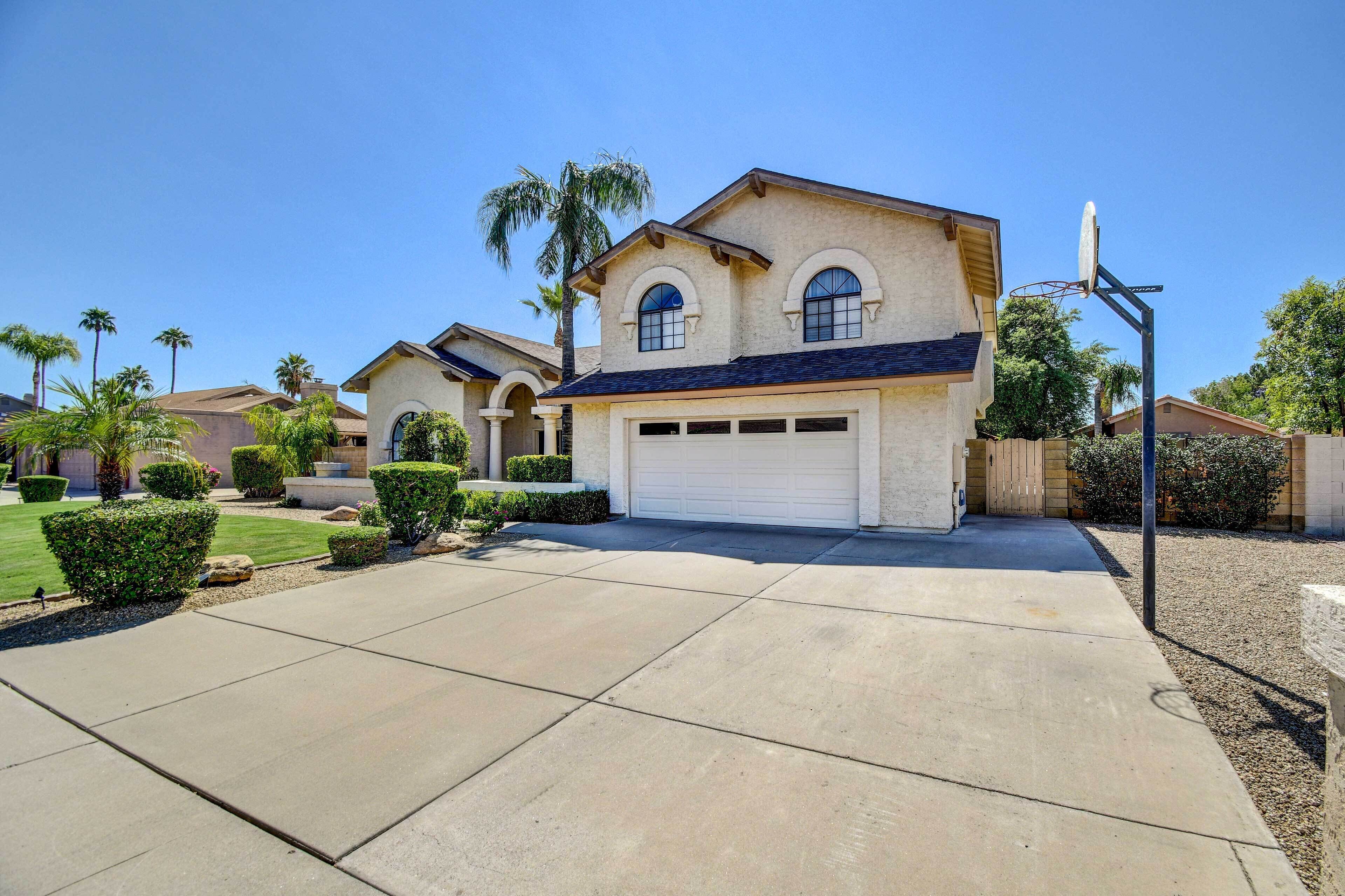 A residential house with a garage, palm trees, and a clear sky.