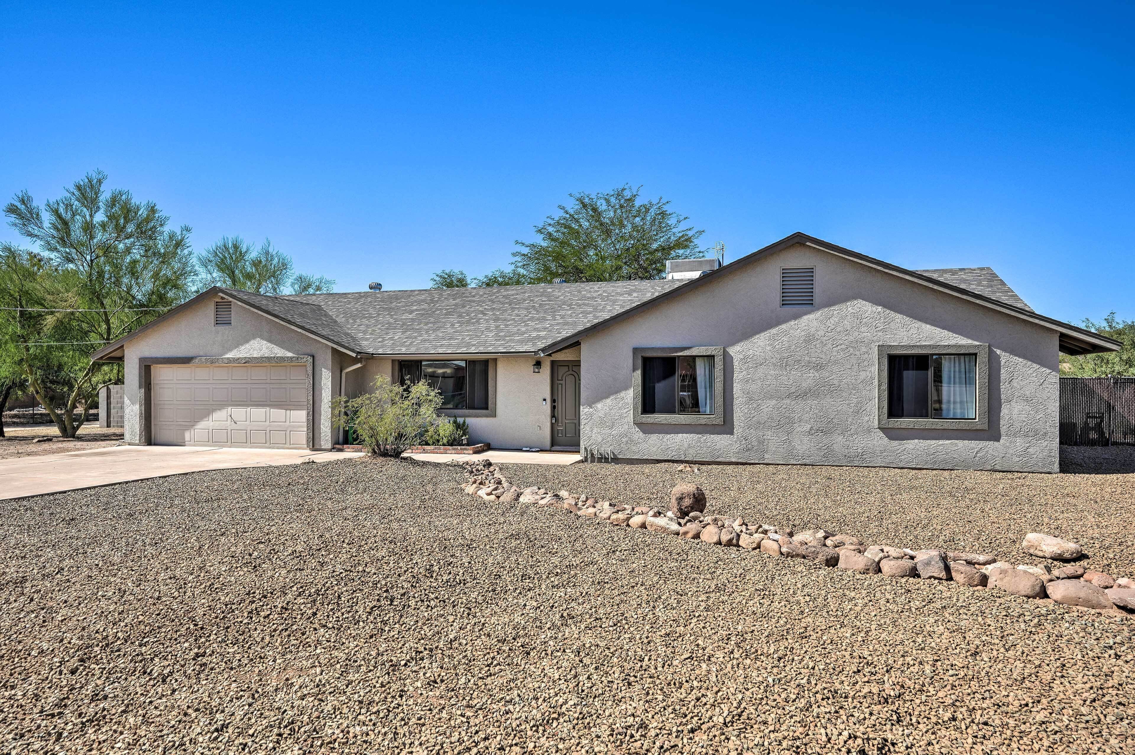 A single-story house with a garage, a covered patio, and a gravel driveway.
