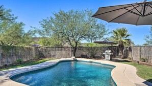 A backyard with a swimming pool, a wooden fence, and a patio umbrella. - Sunny Phoenix Home w/ Pool + Backyard Oasis! (Phoenix)