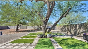 A backyard with a paved pathway, green artificial grass, and potted plants. - Sunny Phoenix Home w/ Pool + Backyard Oasis! (Phoenix)