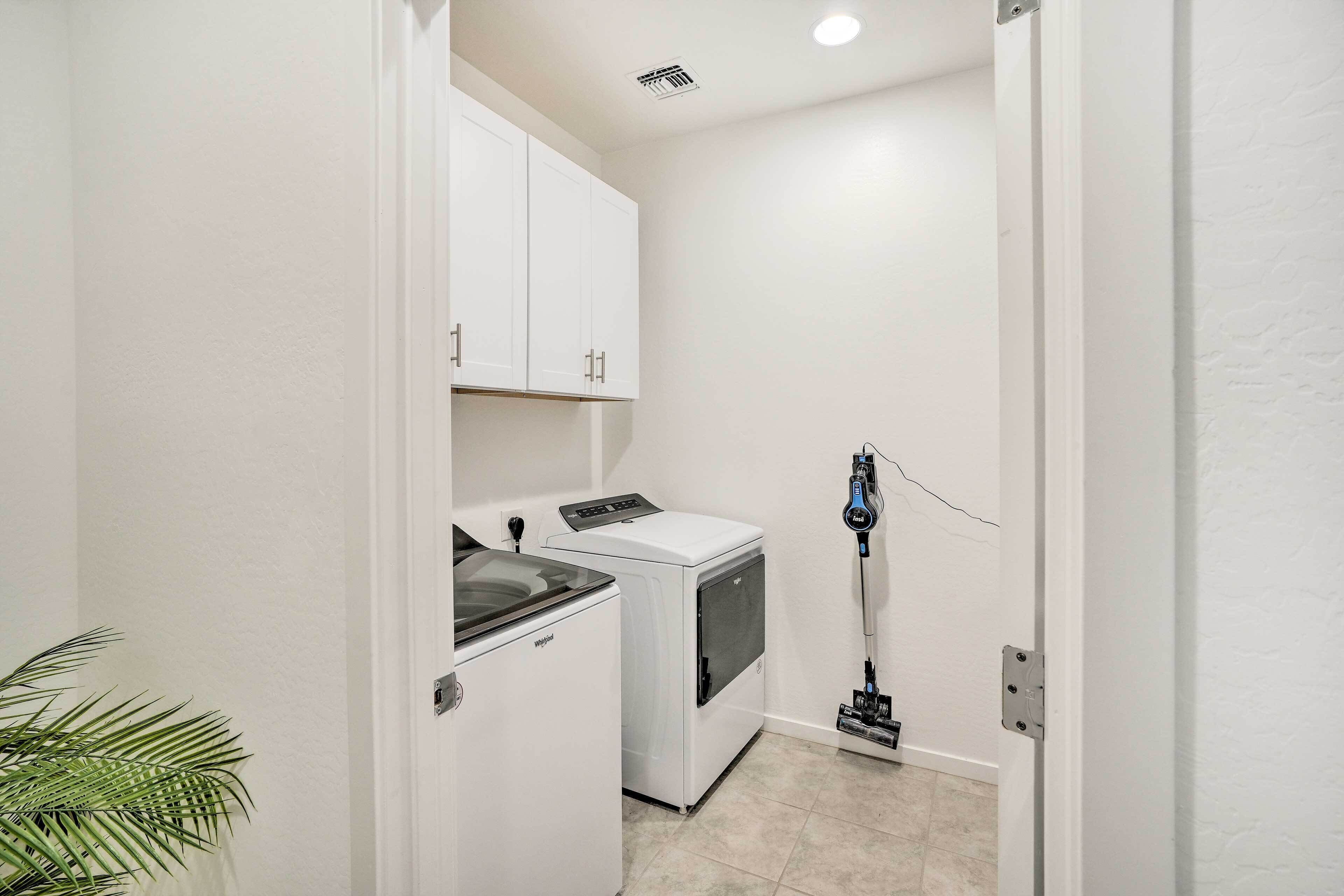 A laundry room with a washing machine, dryer, and a vacuum cleaner.
