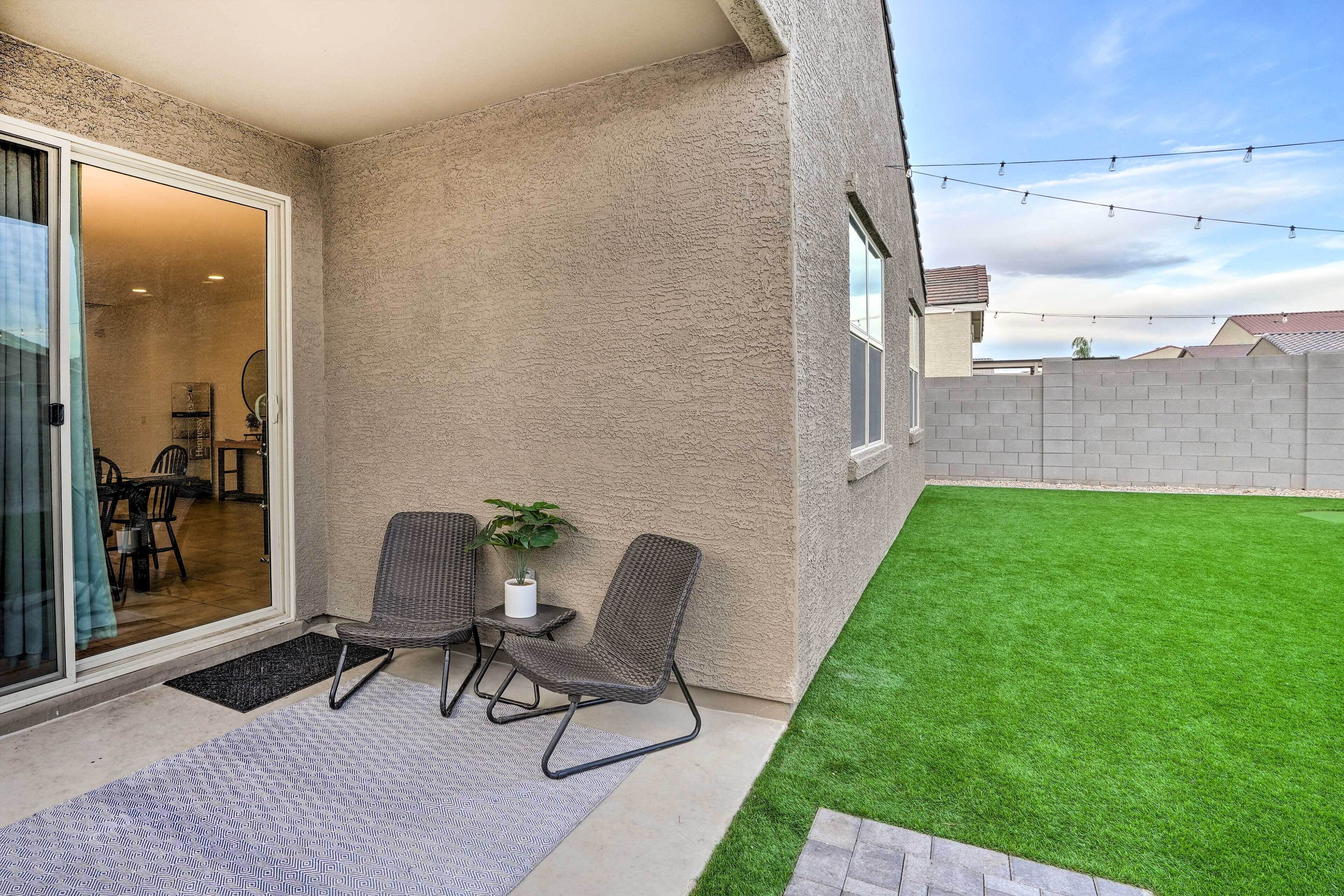 A patio with two wicker chairs, a small table, and a potted plant.