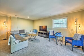 A living room with a sectional sofa, a small round table, a blue armchair, and a flat-screen TV. - Family-friendly Hot Springs Hideaway w/ Yard! (Hot Springs)