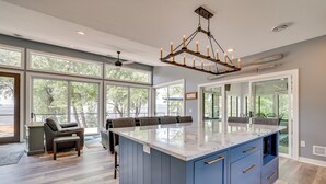 Una cocina amplia con ventanas grandes, una isla central y una lámpara moderna.