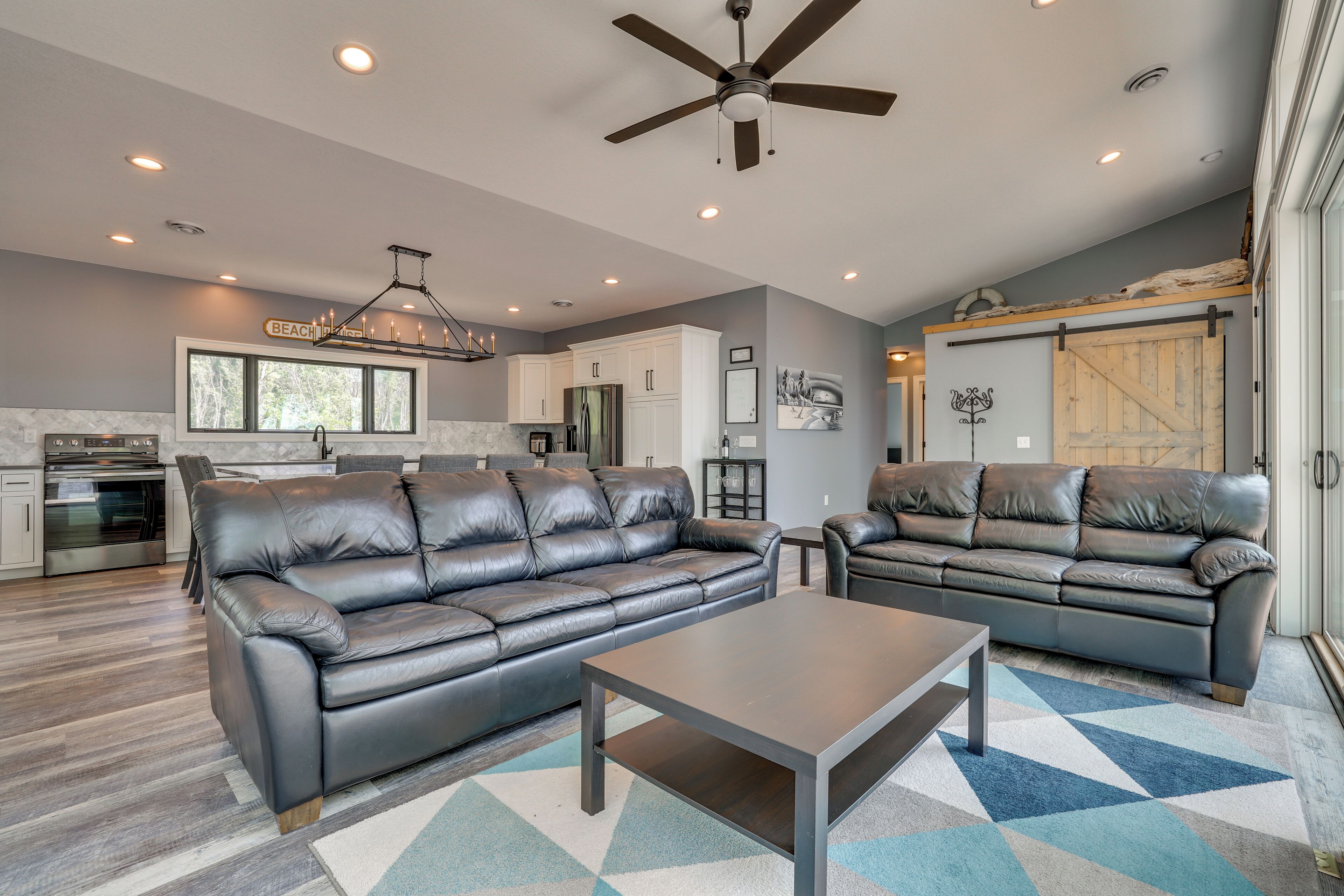 A spacious living room with two leather sofas, a coffee table, and a ceiling fan.