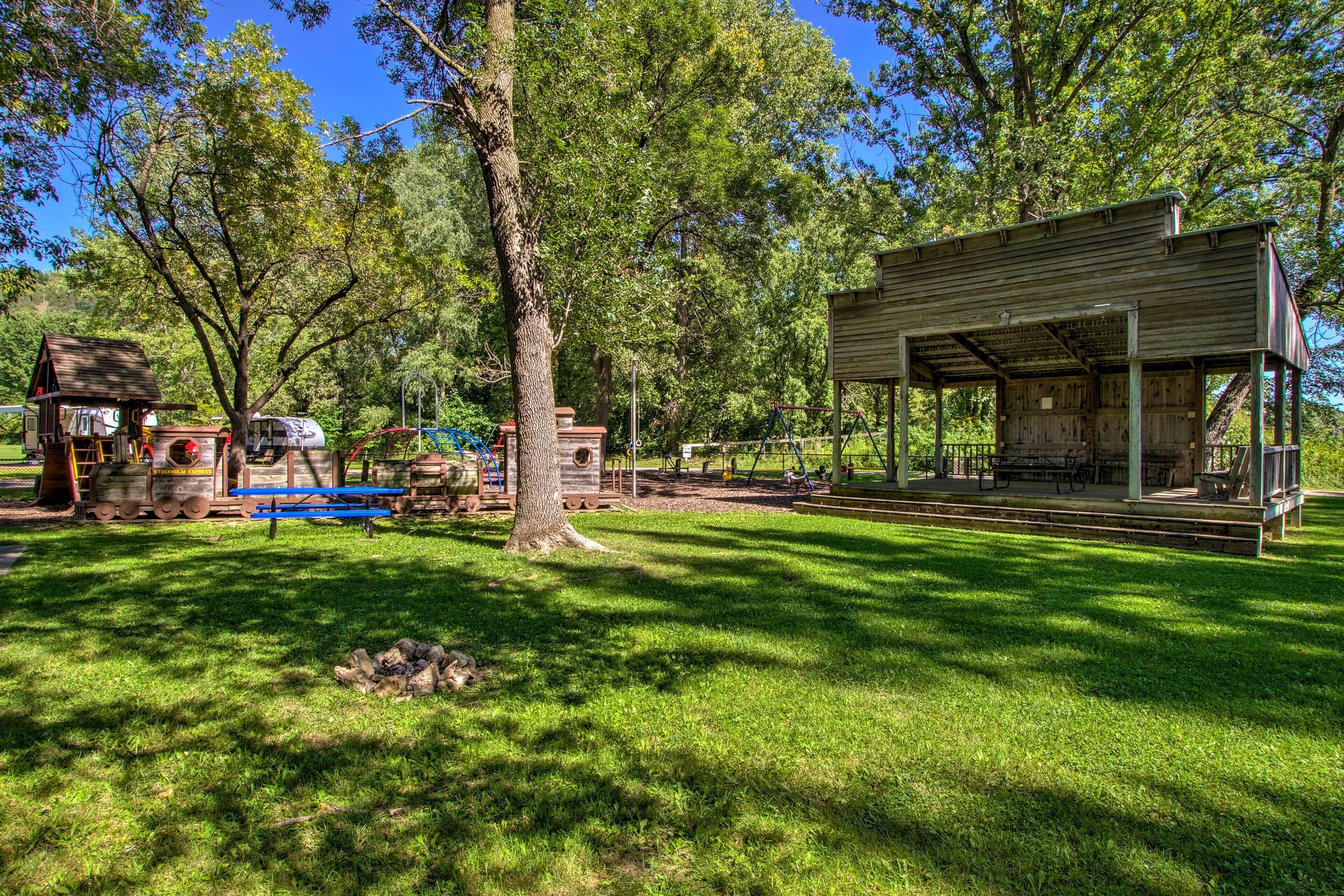A park with a covered picnic area, a small cabin, and a playground.