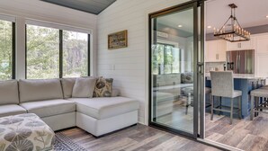 Una cocina moderna con un refrigerador de acero inoxidable, una araña y una zona de comedor con taburetes de bar.