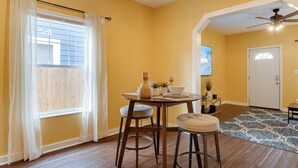 A dining area with a table, two stools, a ceiling fan, and a patterned rug. - Chic Indianapolis Home w/ Yard Near Downtown! (Indianapolis)