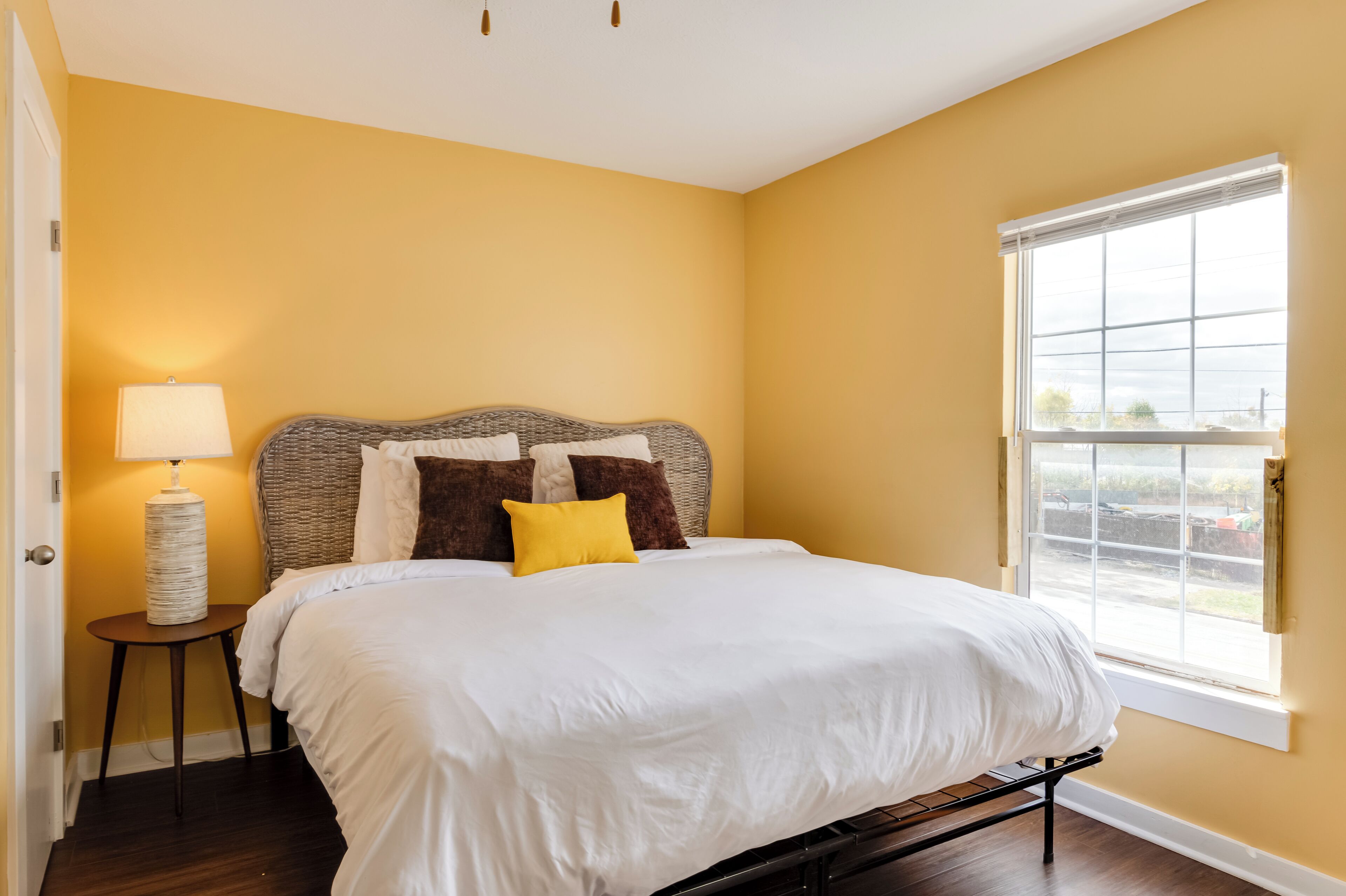 Un dormitorio con cama, lámpara, ventana y vistas al exterior.