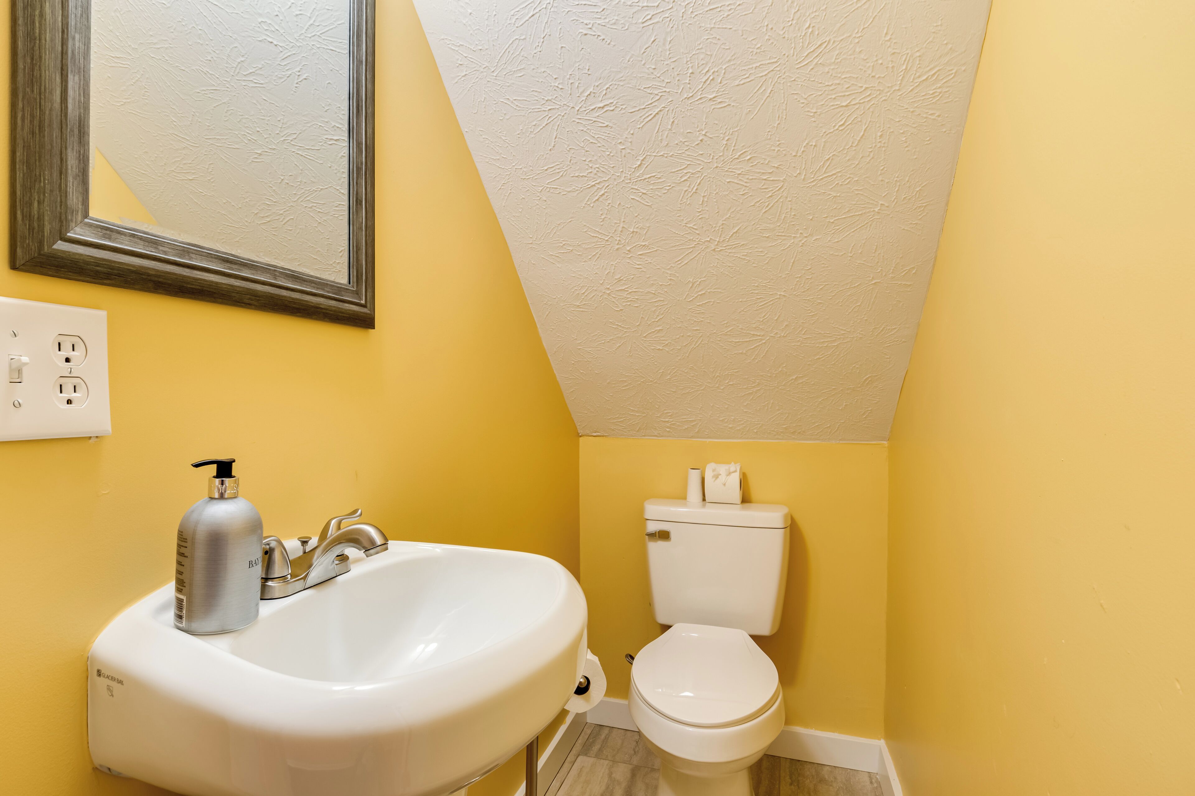 A bathroom with a white sink, a toilet, and a mirror on the wall.