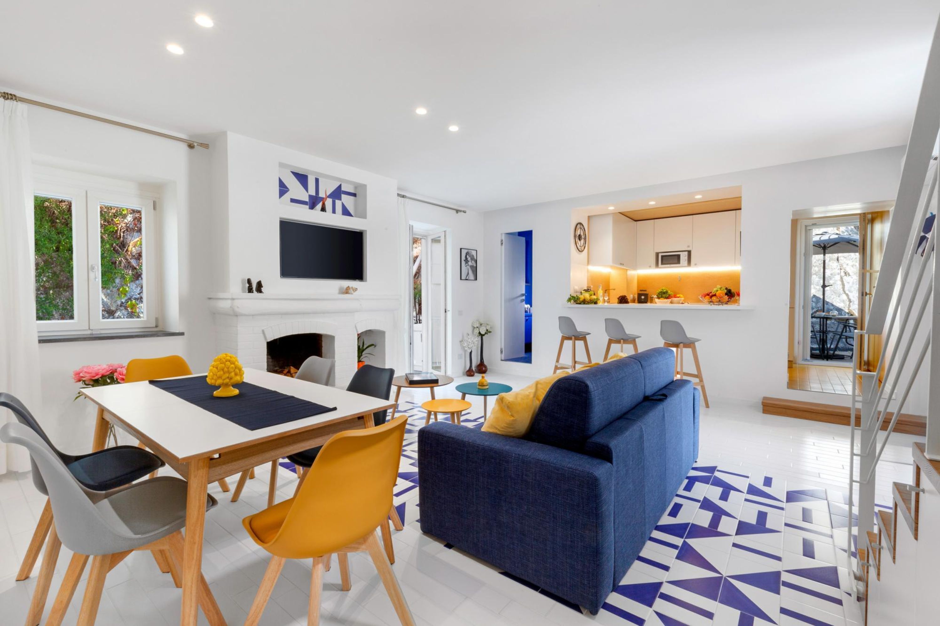 Una sala de estar moderna con comedor, un sofá y una cocina al fondo.