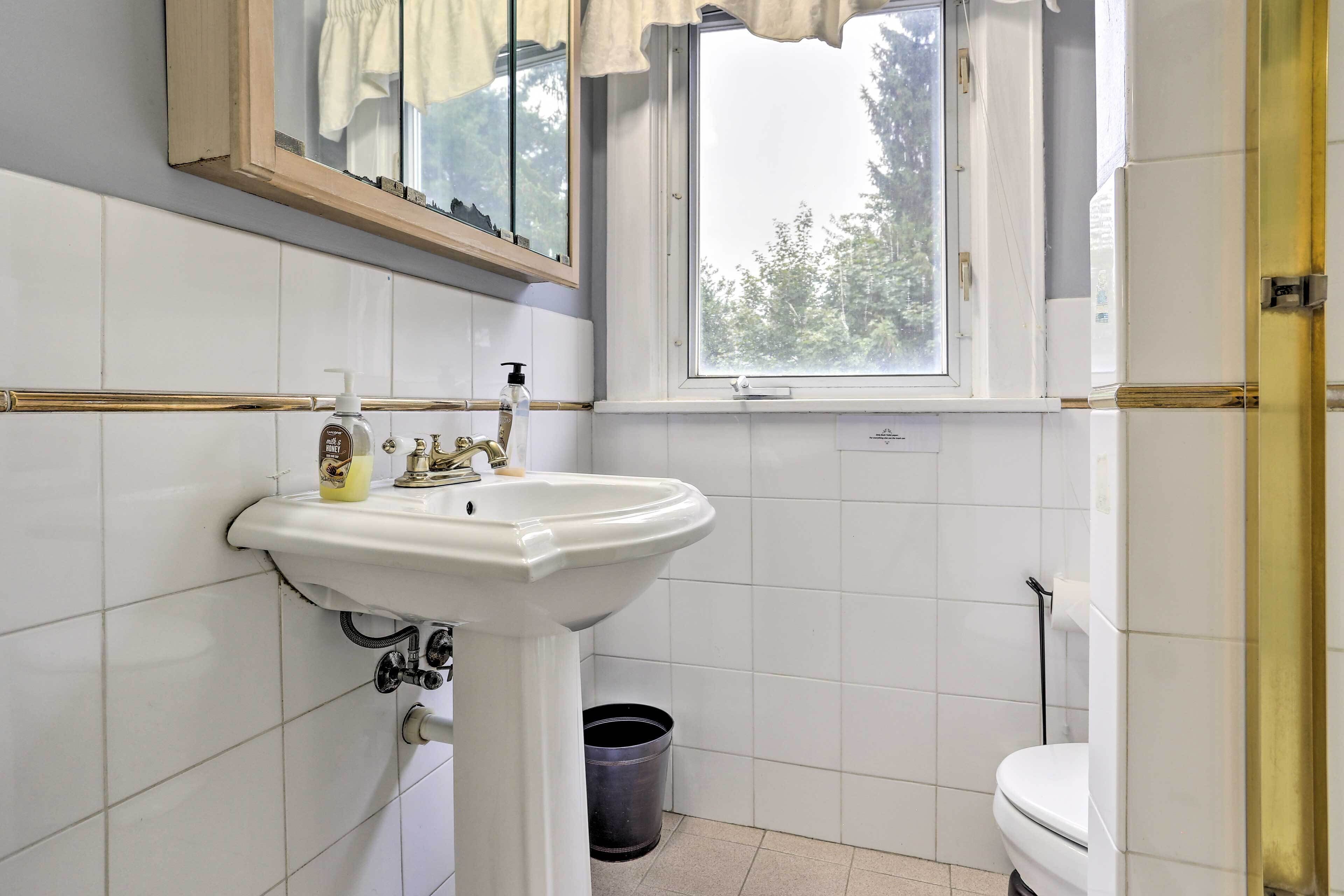 A bathroom with a white sink, a window, and a toilet.