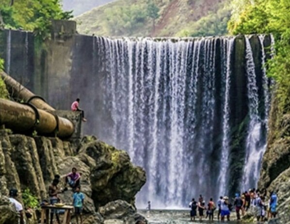 Una cascada con un grupo de personas de pie en la base.