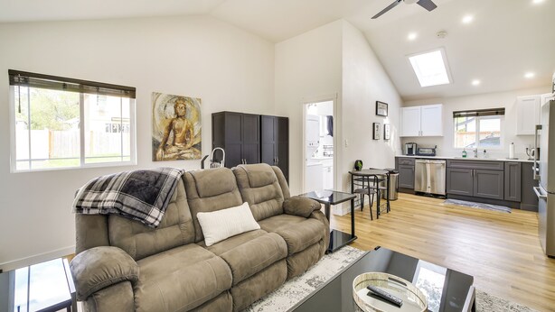 A spacious living room with a large beige sofa, a glass coffee table, and a modern kitchen in the background. - Modern Pacific Vacation Rental: 5 Mi to Lake Tapps (Pacific)