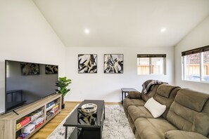 Ein Wohnzimmer mit Flachbildfernseher, Bücherregal, Couchtisch, Sofa und abstrakten Wandbildern.