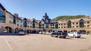 A large building with multiple floors and a central tower, surrounded by a parking lot with several cars. - Cozy Avon Condo Near Beaver Creek Resort! (Avon)