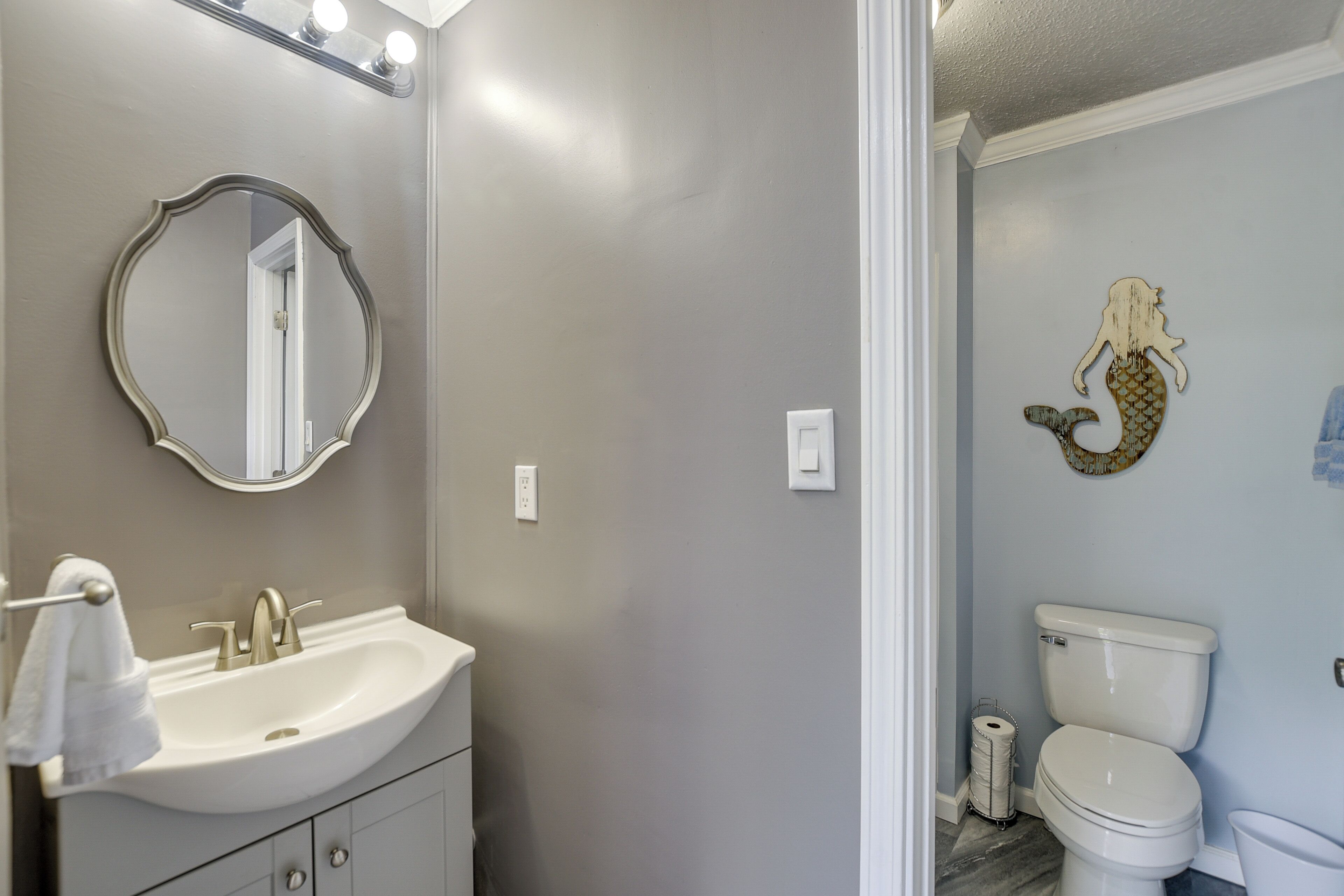 A bathroom with a vanity, sink, mirror, and a toilet.