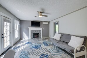Uma sala de estar com lareira, ventilador de teto e sofá.